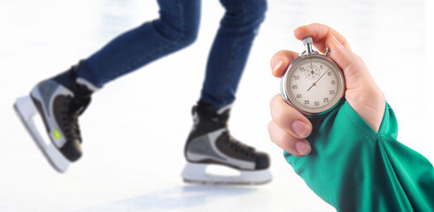 measuring speed on skates with a stopwatch. hand with a stopwatch on the background of the legs of...