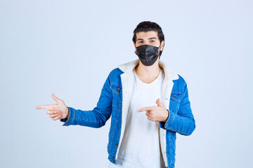 Man wearing black mask and pointing to the left