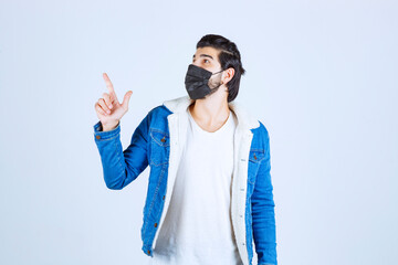 Man in black mask pointing to the up