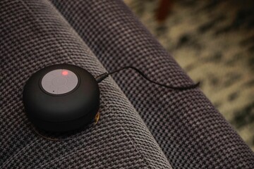 Closeup shot of a small bluetooth speaker charging on the couch