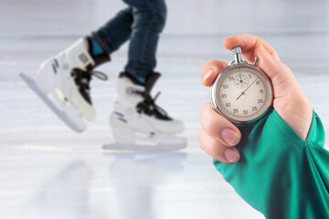 measuring speed on skates with a stopwatch. hand with a stopwatch on the background of the legs of...