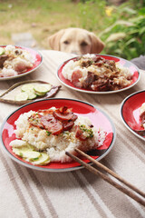 Vertical shot of a pet labrador watching a table full of rice and chinese sausage dishes for breakfast