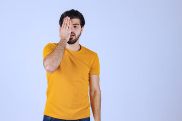 Man in yellow shirt looking through his fingers