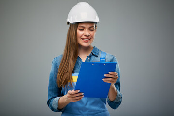 Smiling woman builder wearing overall holding clipboard.