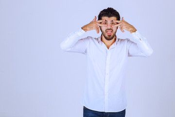 Man with beard looking through his fingers
