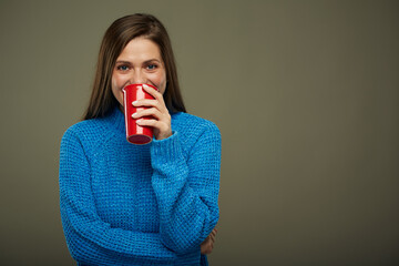 Woman warming with hot drink. Isolated portrait of girl drinking from red glass.