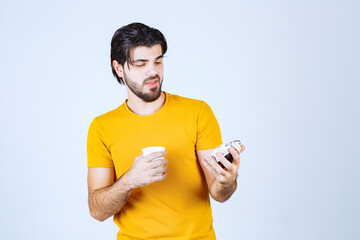 Man holding a coffee cup and alarm clock pointing to morning routine