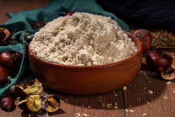 Chestnut flour, unusual vegan gluten-free flour, on wooden background with fresh and roasted chestnuts