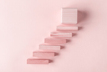 Blank wooden blocks and cube arranged as stairs on pink background