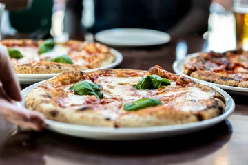 Foto auf Glas Close up view of a Margherita Neapolitan style pizza with buffalo mozzarella, tomato sauce and basil - Waiter hand serving pizza at pizza restaurant © Davide Zanin