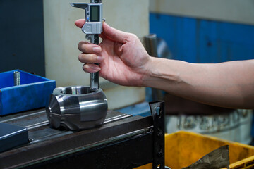 Hands of an engineer measures a metal part with a digital vernier caliper. Quality control of part machined on a lathe,Quality control concept of Qc.