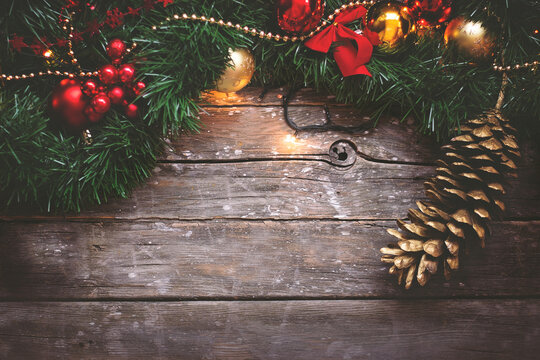 Christmas background - garland, golden and red ornaments and pine cone on dark wooden background