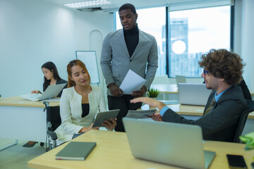 Asian woman who use the wheelchair working in office with diversity of colleague.