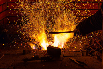 Burning fire with sparks and red-hot metal ready to be forged in a forge. Blacksmithing manufacture.