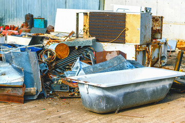 Old iron bath in selective focus along with out of focus scrap metal for recycling at an industrial waste collection center. Transportation of metal waste.