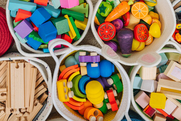 Colorful Toy Storage Baskets in the children's room. Cloth stylish Baskets with wooden toys. Organizing and Storage Ideas in nursery. Clean up toys and reduce the clutter. Top view