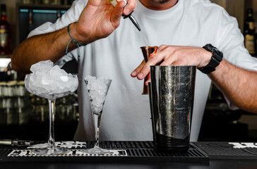 Barman preparando cóctel en coctelería con utensilios de barman con vasos con mucho hielo