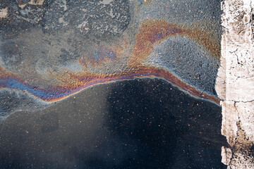 Gasoline spill on asphalt in a car park as a texture or background.