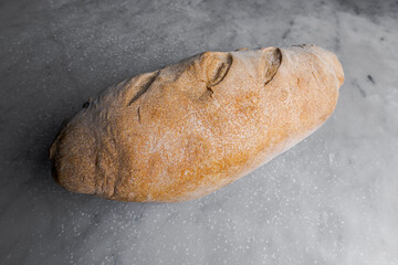 Barra de pan artesanal hecha en restaurante en estilo italiano apoyado en mesa de mármol