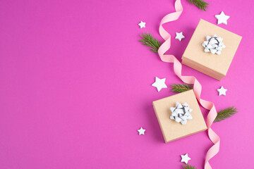 Christmas holiday background with little gift boxes, stars and fir branches, pink trendy background
