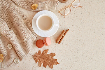 Feminine fall cozy home lifestyle - sweater, glasess. Atmospheric coffee time among oak leaves, cinnamon sticks, macaroons . Copy space.