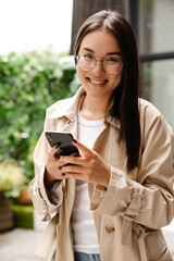 Young asian woman using cellphone while drinking coffee