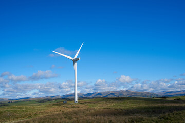 A wind turbine in Cumbria set against the Howgills in the background, shot in landscape on a sunny day with bright blue skies