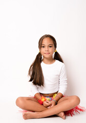 Close up of little child girl in hawaiian costume sitting on the floor isolated white background