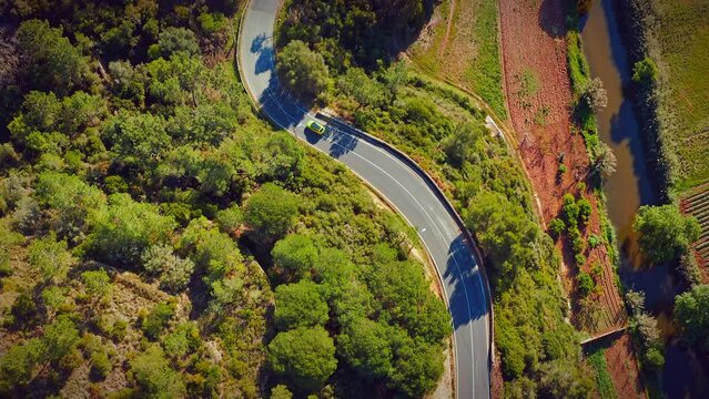 Aerial view of a beautiful hilly area with a highway. Drone view of a winding road in a mountainous area with moving cars on an asphalt road.  Cars are driving in a scenic area, top view. Portugal.