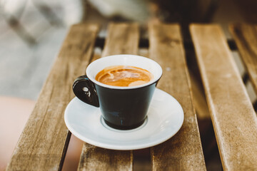 Cup of black coffee on a table in a street cafe.
