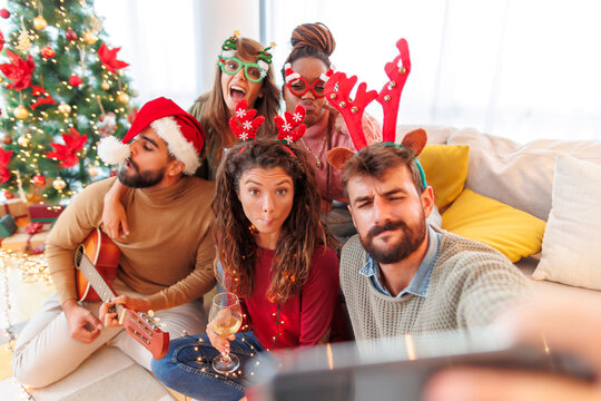Friends having fun taking selfies while celebrating Christmas at home - Powered by Adobe
