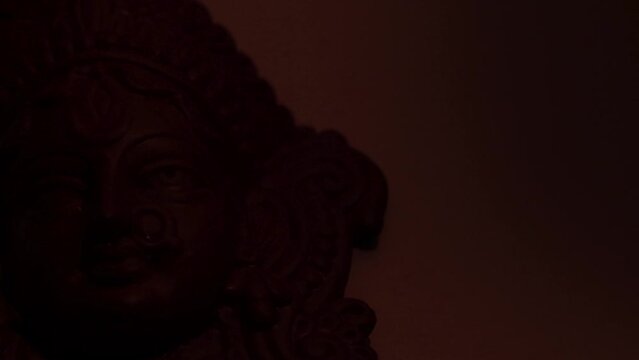 terracotta sculpture of face of goddess Durga for Durga Puja festival in west bengal india. shot against white background in partial lighting condition. idol of Hindu goddess made of clay.