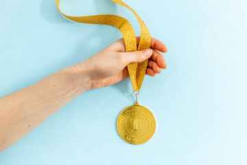 Plakat Hand holding up gold medal first place. Winner concept