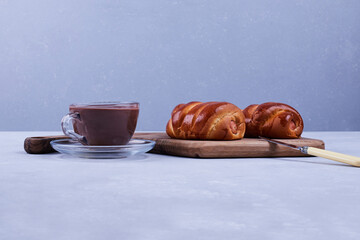 Sweet buns with a cup of tea on blue background