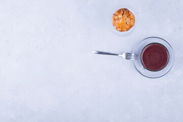 A cupcake in a glass cup served with hot chocolate