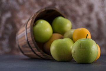 Green apples and oranges out of a wooden bucket