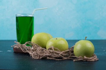 Green apples with a glass of juice on a wooden board