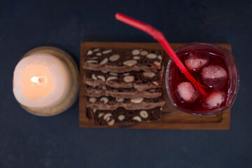 A glass of red juice with cake slices on a wooden platter, top view