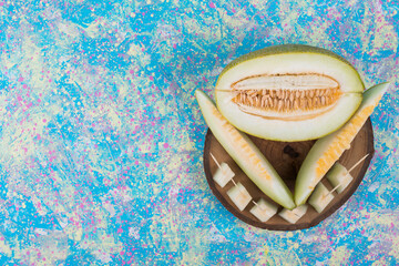 Slices and cubes of melon on a wooden platter, top view