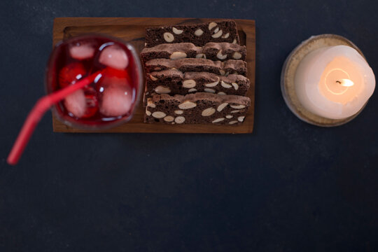 Red Cocktail With Ice Cubes In A Glass With A Slice Of Cake, Top View