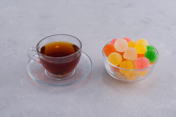 A cup of colorful marmelades with a glass of earl grey tea, angle view