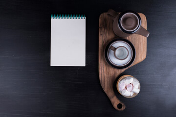 Coffee kettle with a cup and marshmallows and a notebook aside