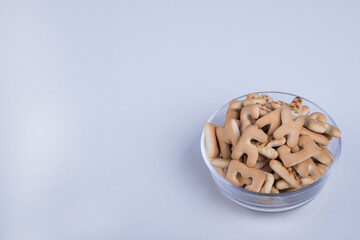 Vanilla crackers in letter shape in a glass cup, angle view