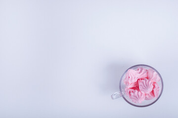 Pink flower shape marshmallows in a glass cup on the bottom corner