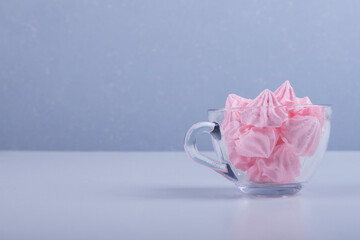Pink flower shape marshmallows in a glass cup in the right side