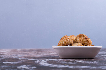 Crunchy cookies in a white ceramic saucer on blue background