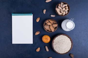 Dry fruits and ingredients with a jar of milk with a notebook aside