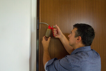 Picture of a handyman who with an oiler lubricates the hinges of a creaking door. Housework and...