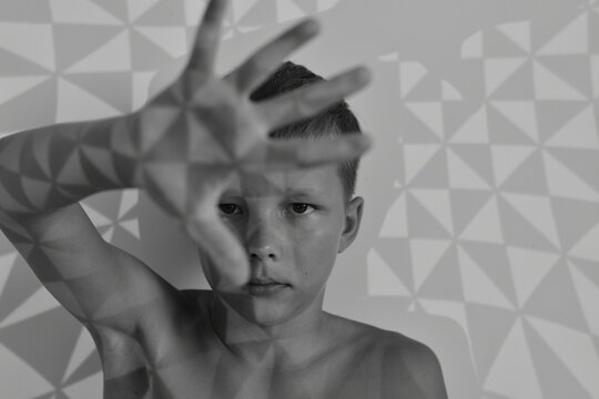 A Young Boy Model Stretched Out His Hand In Front Of Him With Spread Fingers In A Black And White Photo.