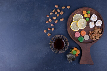 Obraz na płótnie Canvas Wooden snack platter with candies and a glass of tea, top view